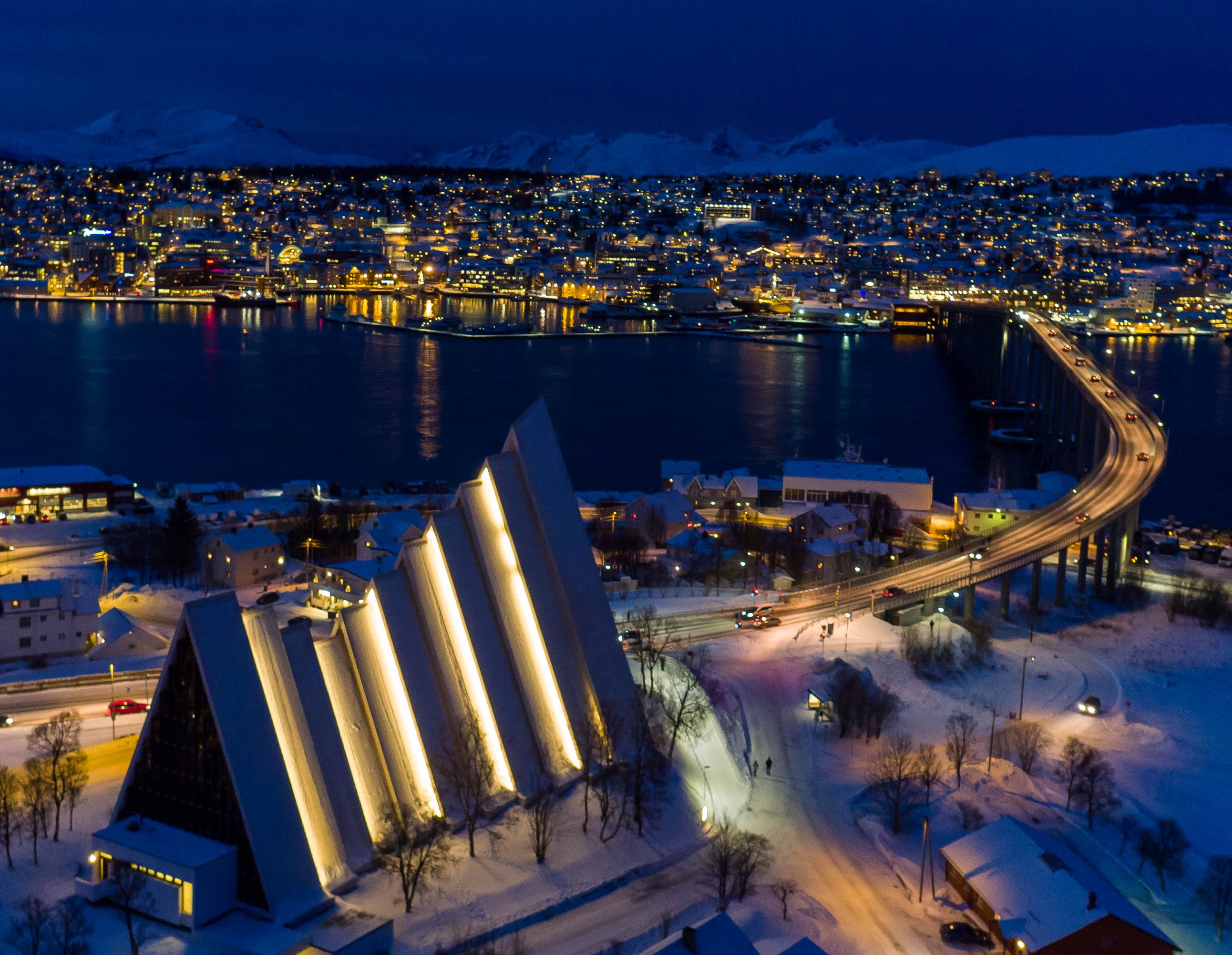 Ishavskatedralen lyser opp i mørket med byen i bakgrunnen